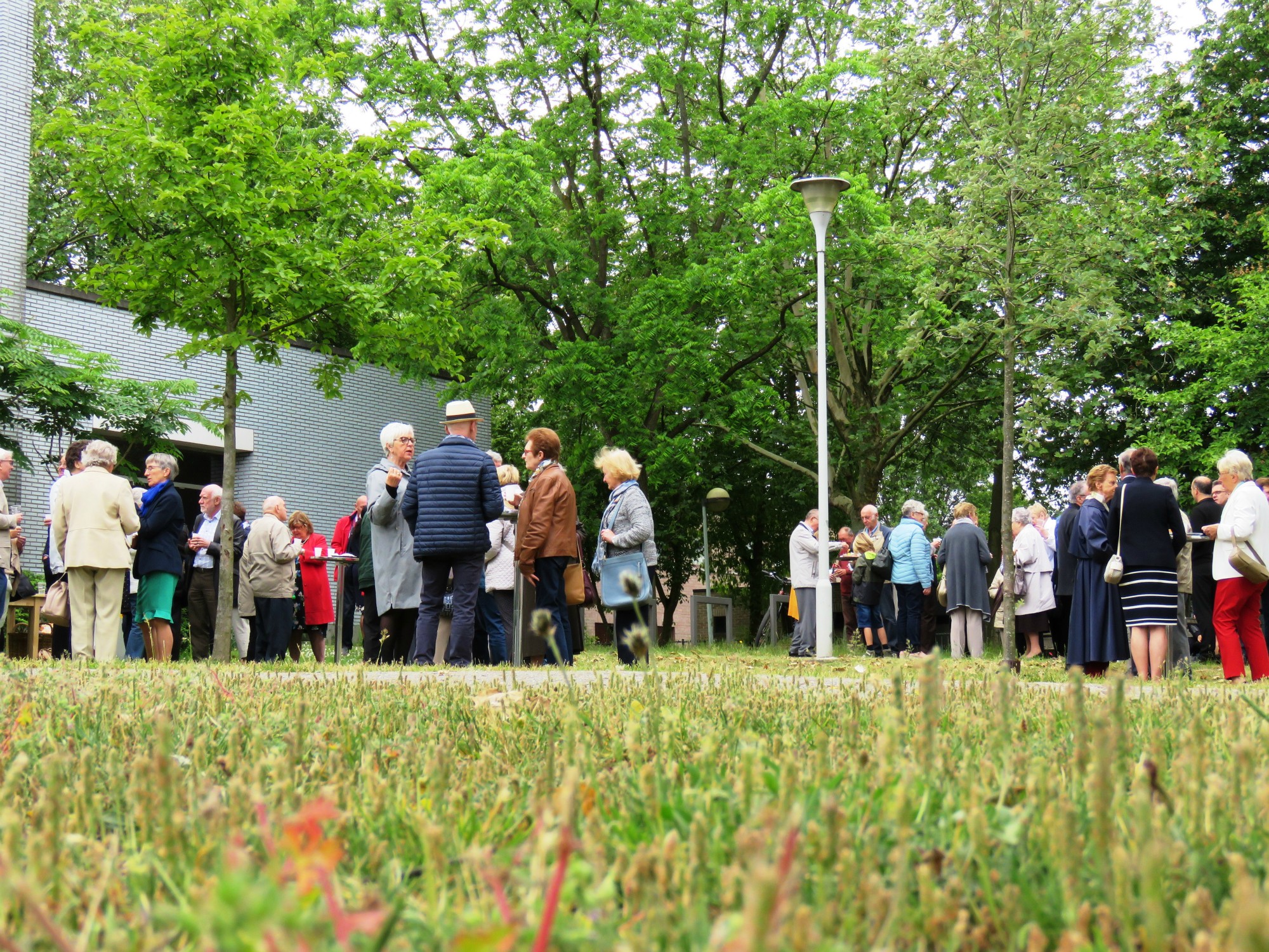 Receptie t.g.v. Rerum Novarum op het gras voor de kerk