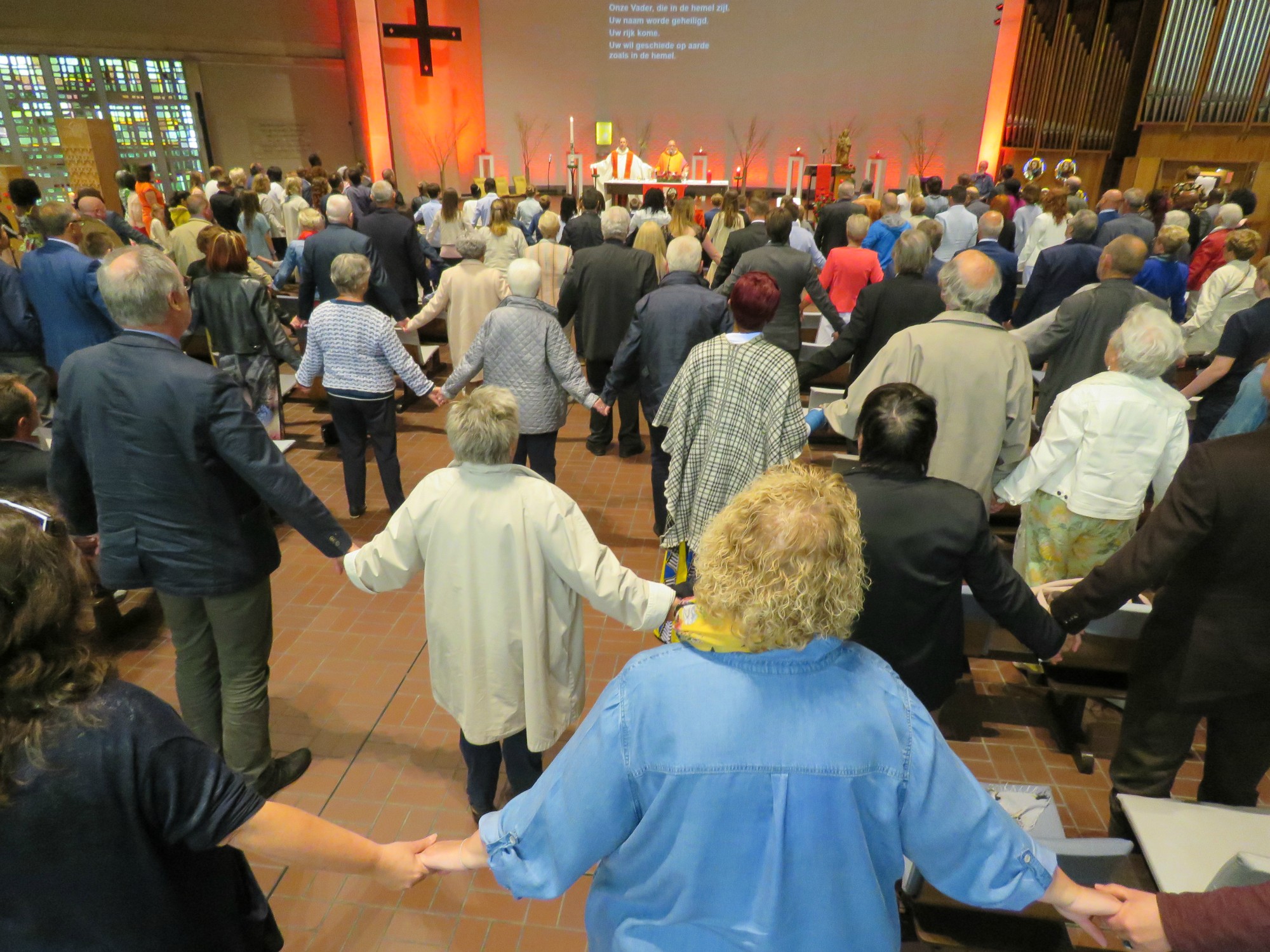 Het Onze Vader, hand in hand, over de rijen heen