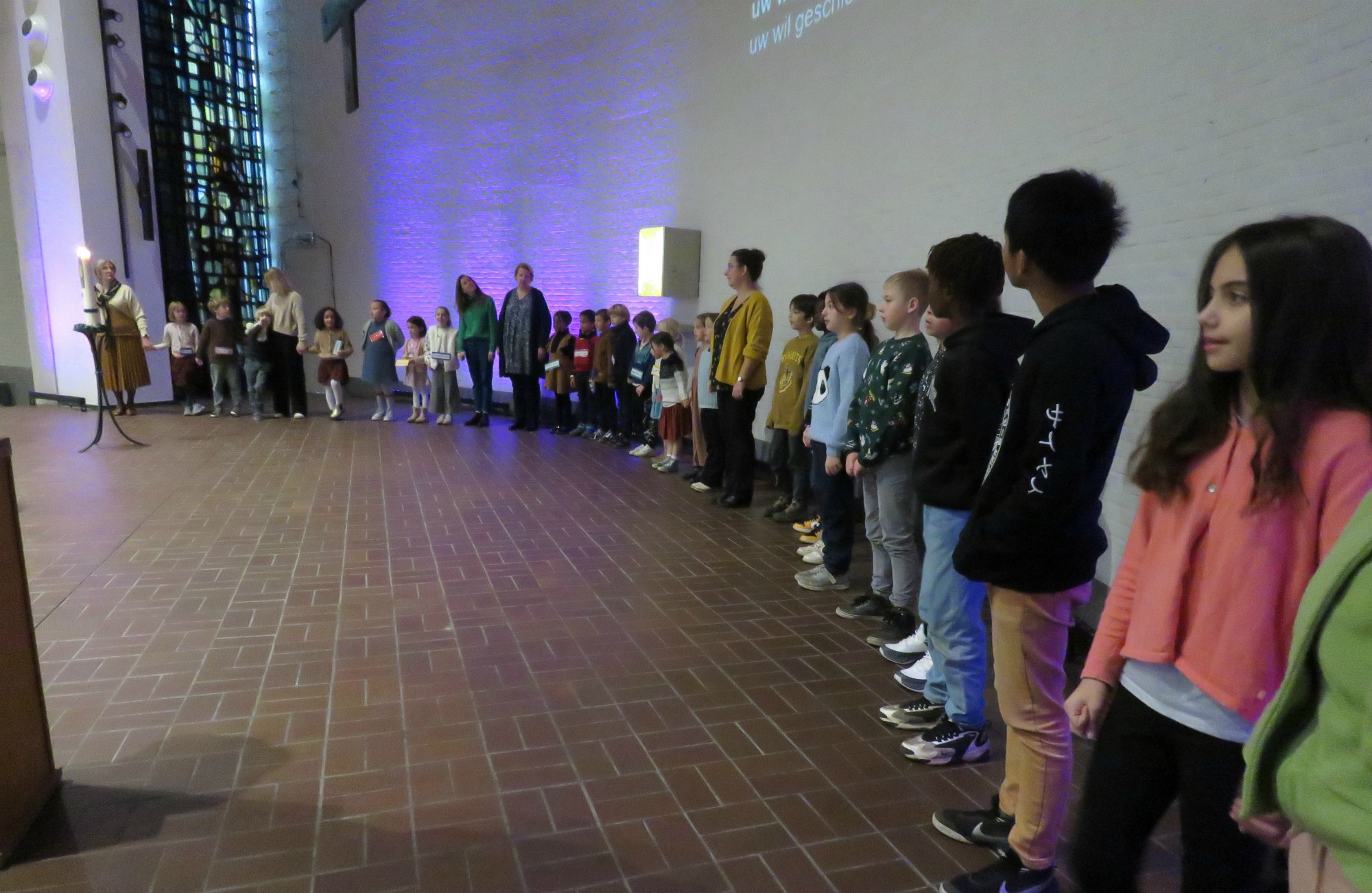 Alle kinderen voor het Onze Vader en vredeswens rondom het altaar in een grote kring