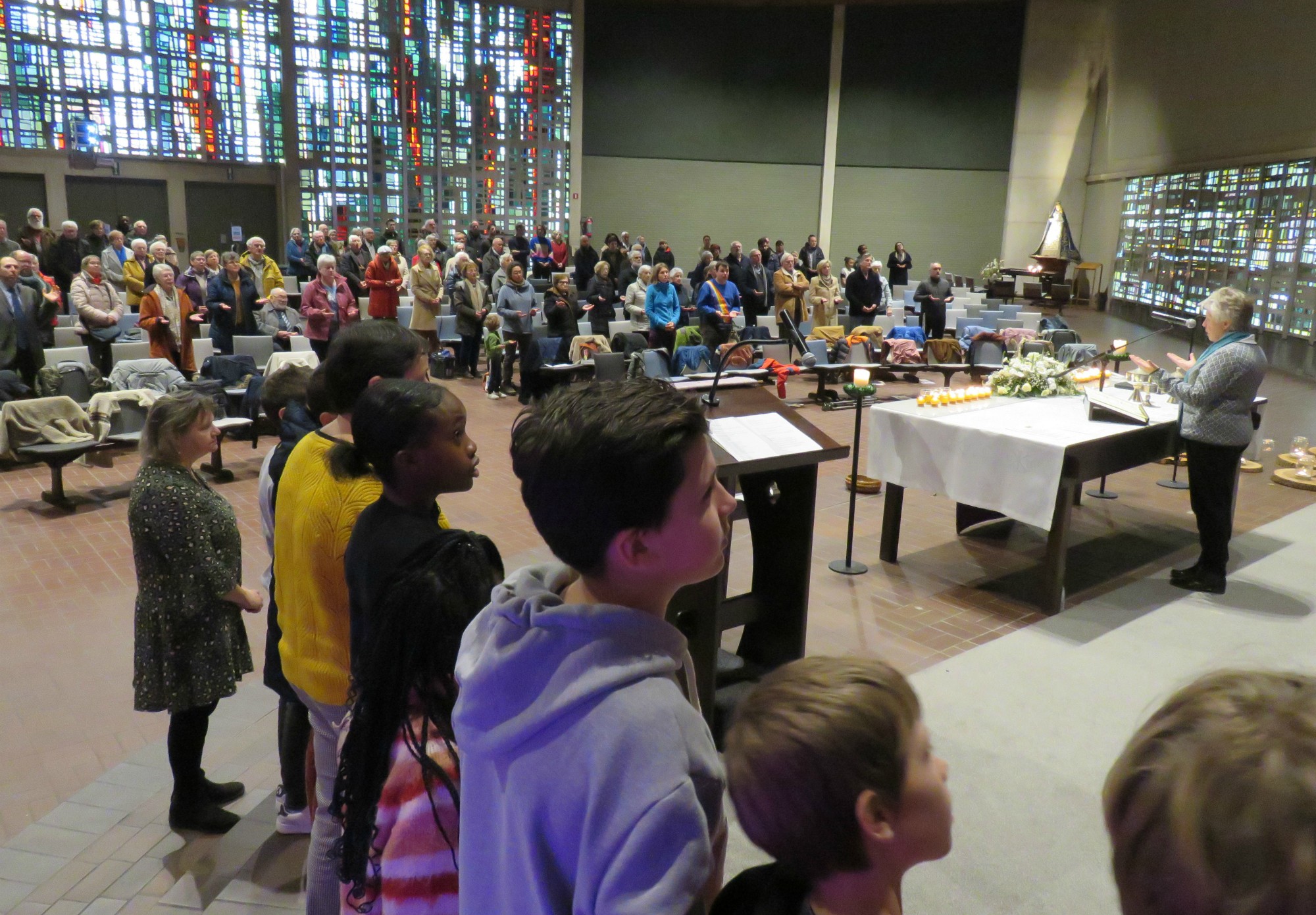 Alle kinderen voor het Onze Vader en vredeswens rondom het altaar in een grote kring