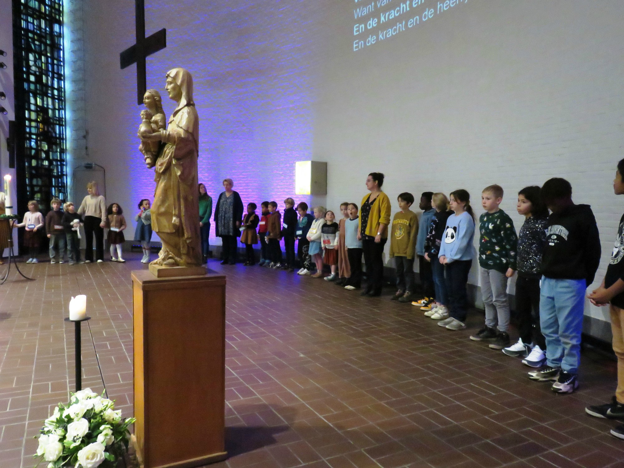 Alle kinderen voor het Onze Vader en vredeswens rondom het altaar in een grote kring