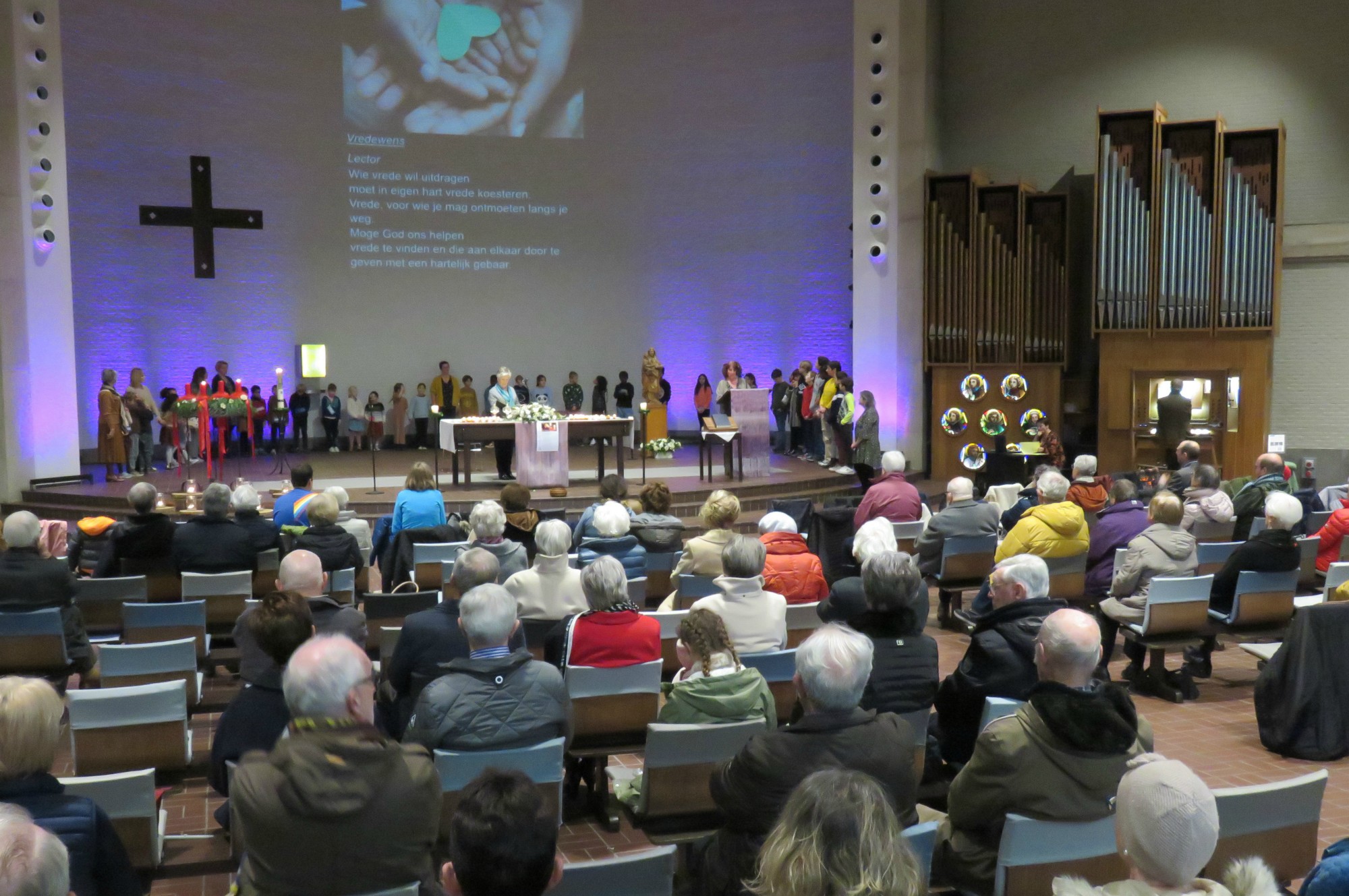 Alle kinderen voor het Onze Vader en vredeswens rondom het altaar in een grote kring