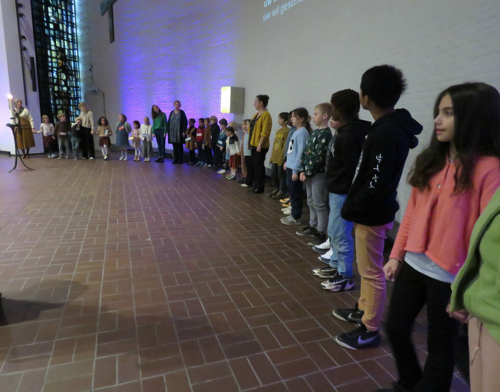 Alle kinderen voor het Onze Vader en vredeswens rondom het altaar in een grote kring