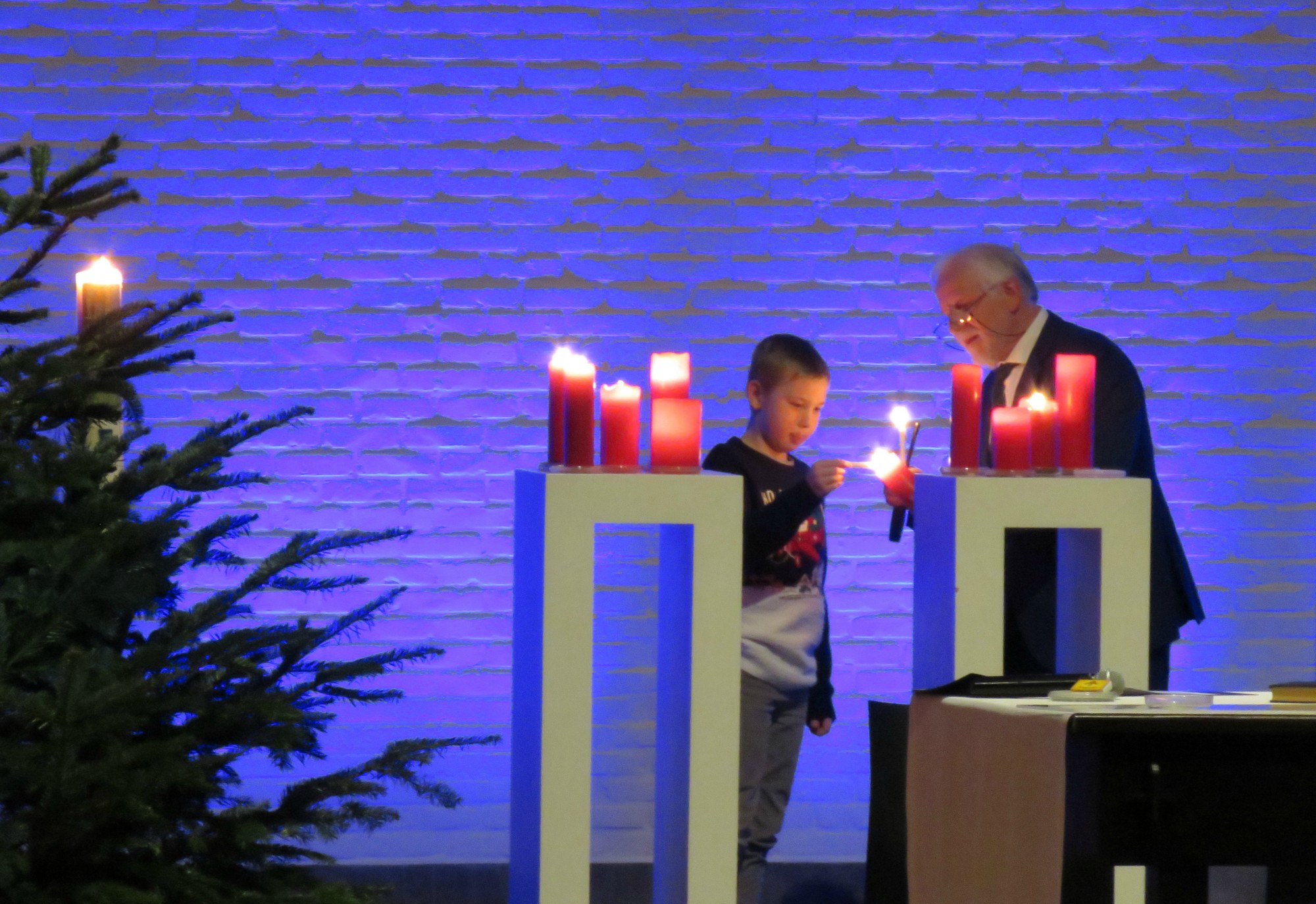 Een vormeling ontsteekt alle rode kaarsen achter het altaar bij de Lichtritus