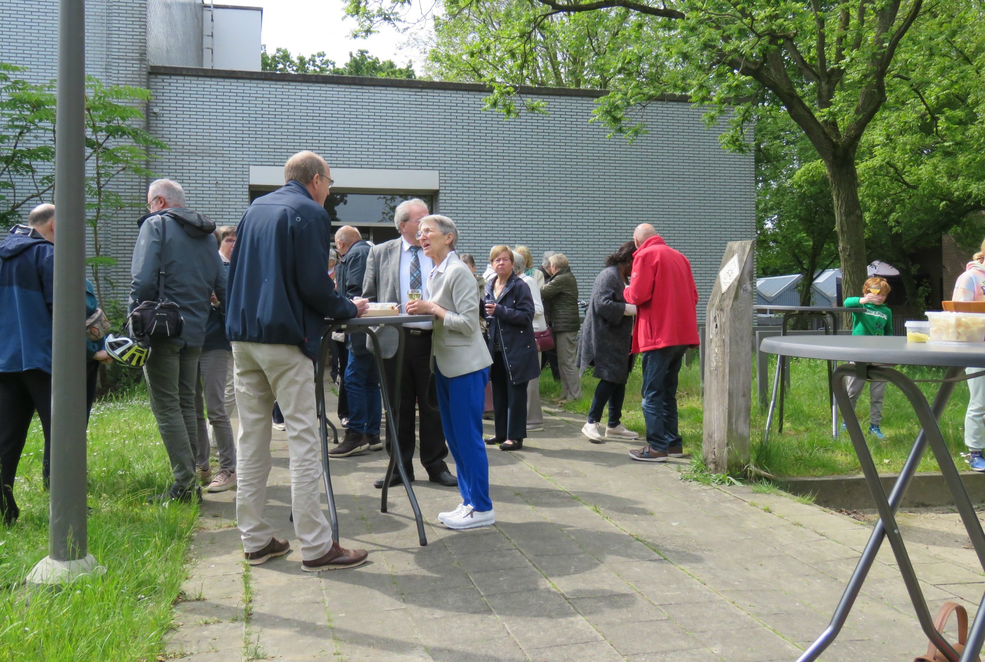 Receptie met deelmoment na de vieiring buiten in de zon aan de Sint-Anna-ten-Drieënkerk, Antwerpen Linkeroever