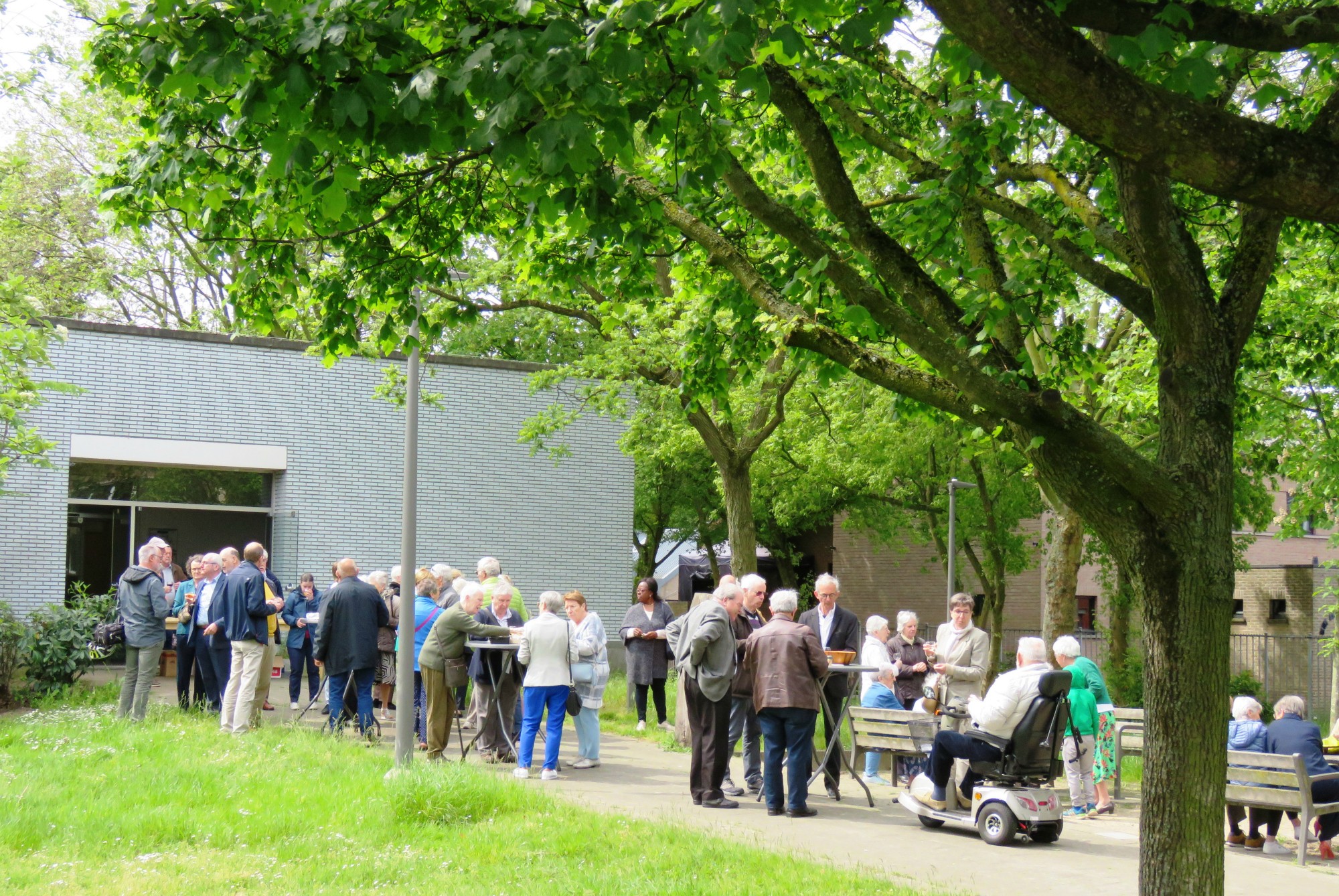 Receptie met deelmoment na de vieiring buiten in de zon aan de Sint-Anna-ten-Drieënkerk, Antwerpen Linkeroever