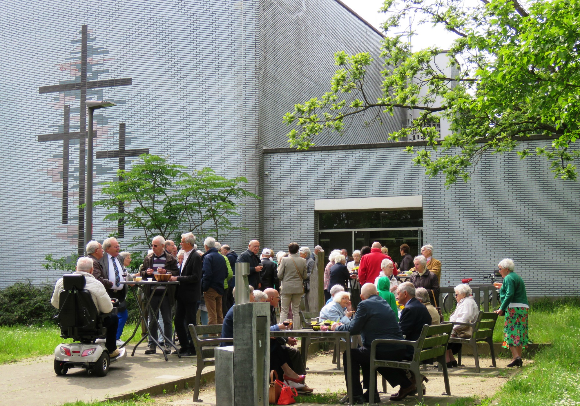 Receptie met deelmoment na de vieiring buiten in de zon aan de Sint-Anna-ten-Drieënkerk, Antwerpen Linkeroever