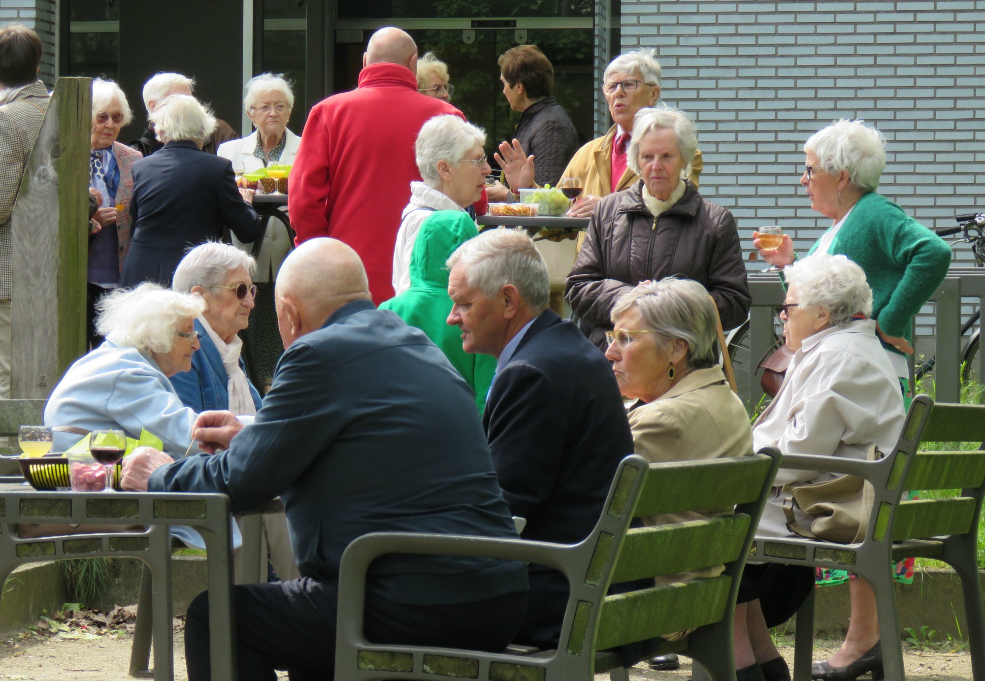 Receptie met deelmoment na de vieiring buiten in de zon aan de Sint-Anna-ten-Drieënkerk, Antwerpen Linkeroever