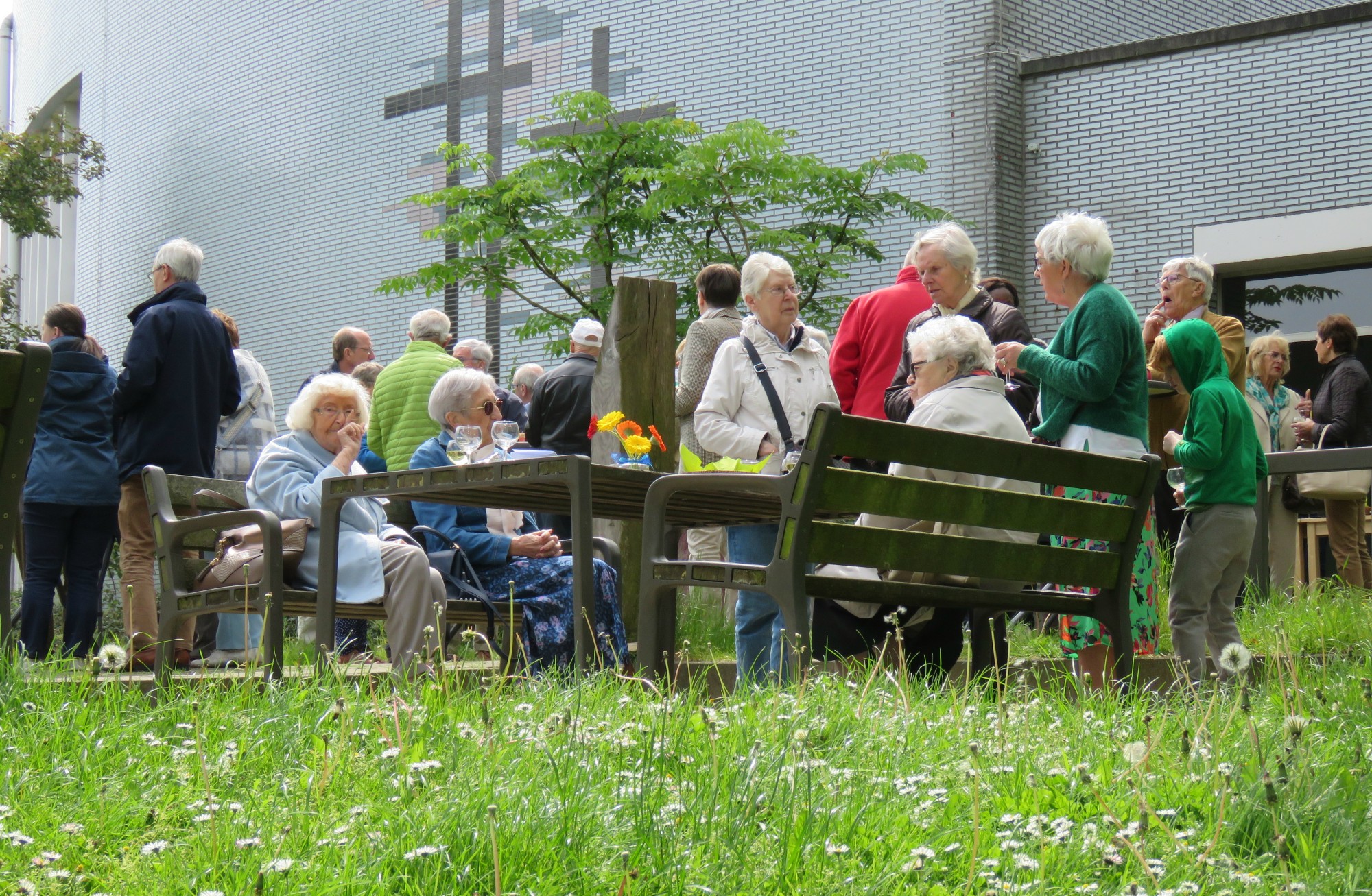 Receptie met deelmoment na de vieiring buiten in de zon aan de Sint-Anna-ten-Drieënkerk, Antwerpen Linkeroever