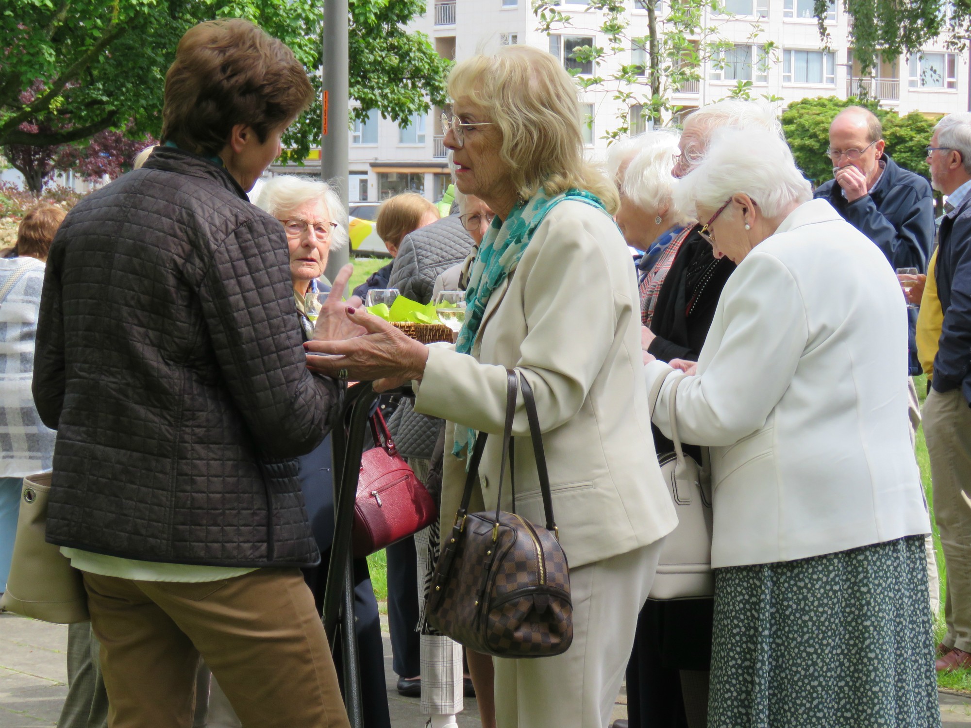 Receptie met deelmoment na de vieiring buiten in de zon aan de Sint-Anna-ten-Drieënkerk, Antwerpen Linkeroever