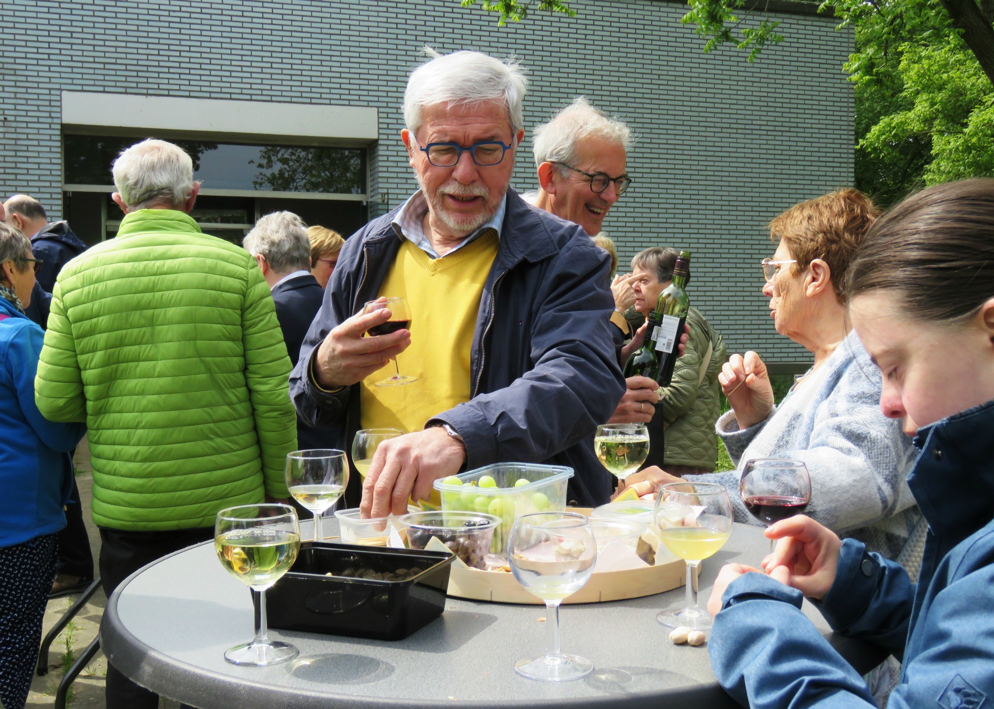 Receptie met deelmoment na de vieiring buiten in de zon aan de Sint-Anna-ten-Drieënkerk, Antwerpen Linkeroever