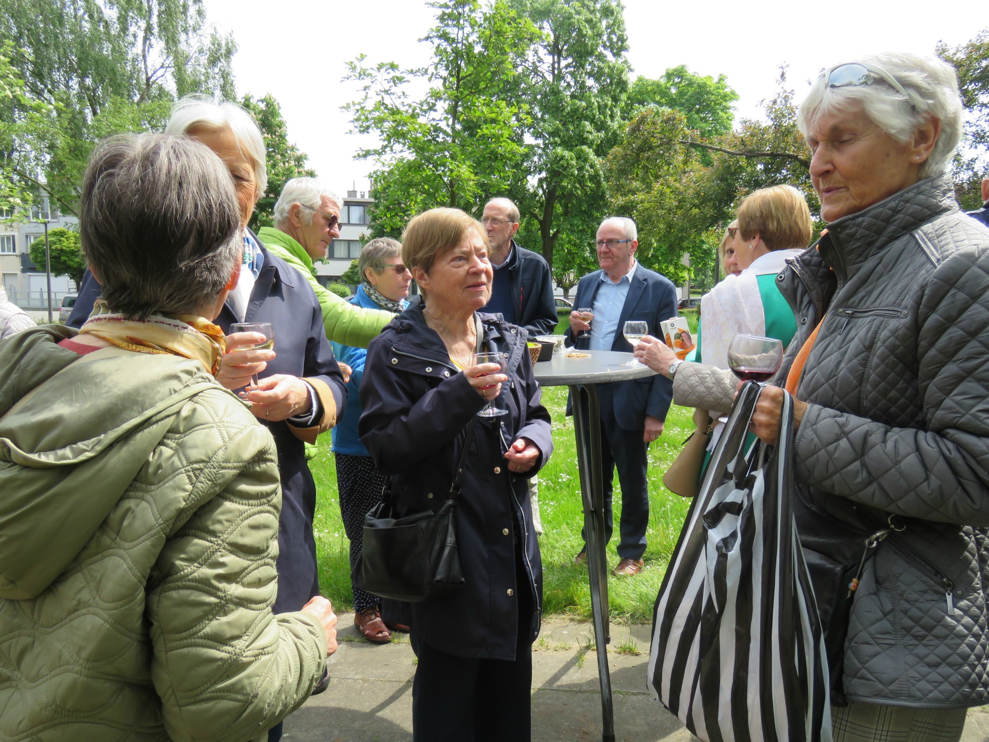 Receptie met deelmoment na de vieiring buiten in de zon aan de Sint-Anna-ten-Drieënkerk, Antwerpen Linkeroever