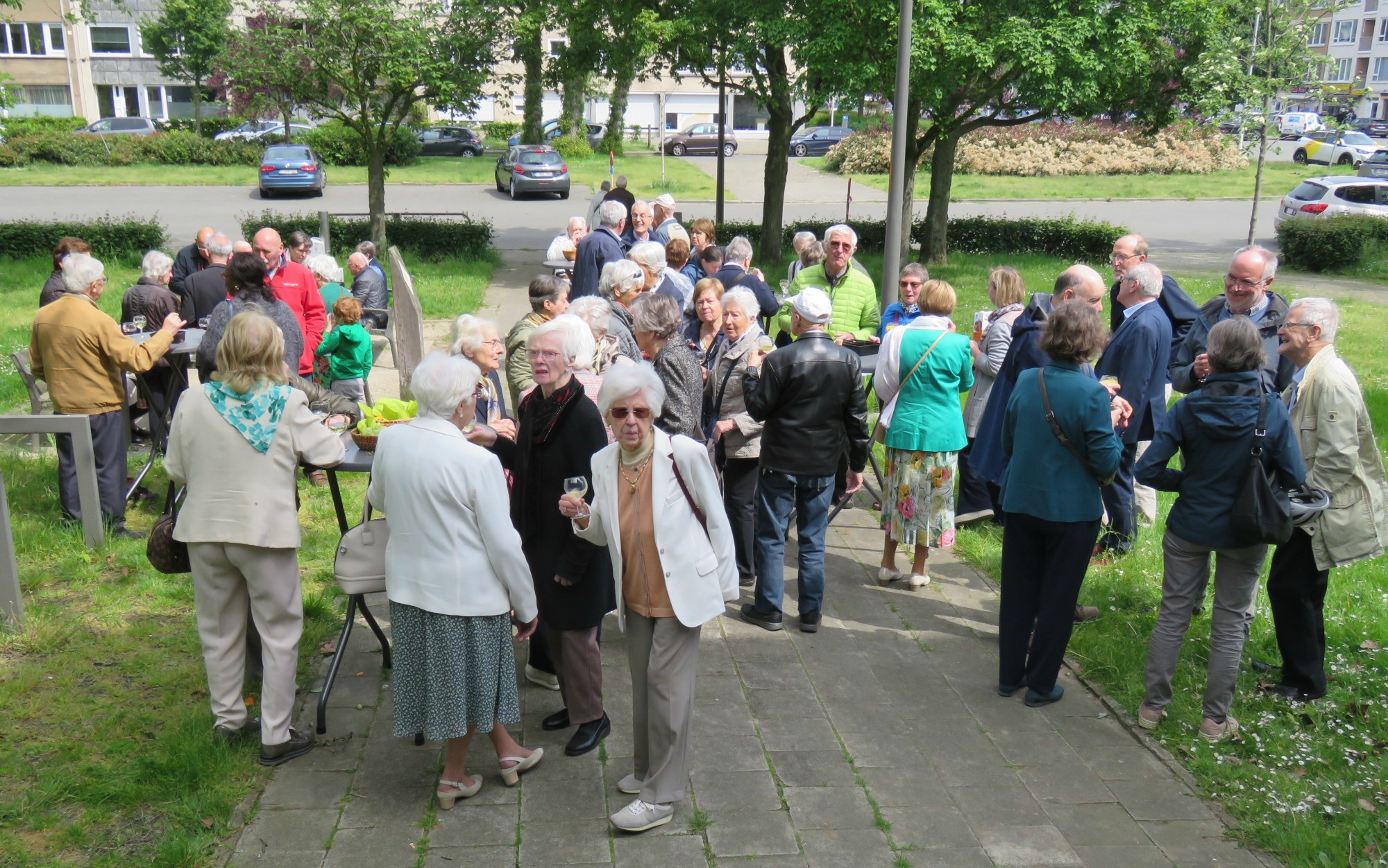 Receptie met deelmoment na de vieiring buiten in de zon aan de Sint-Anna-ten-Drieënkerk, Antwerpen Linkeroever