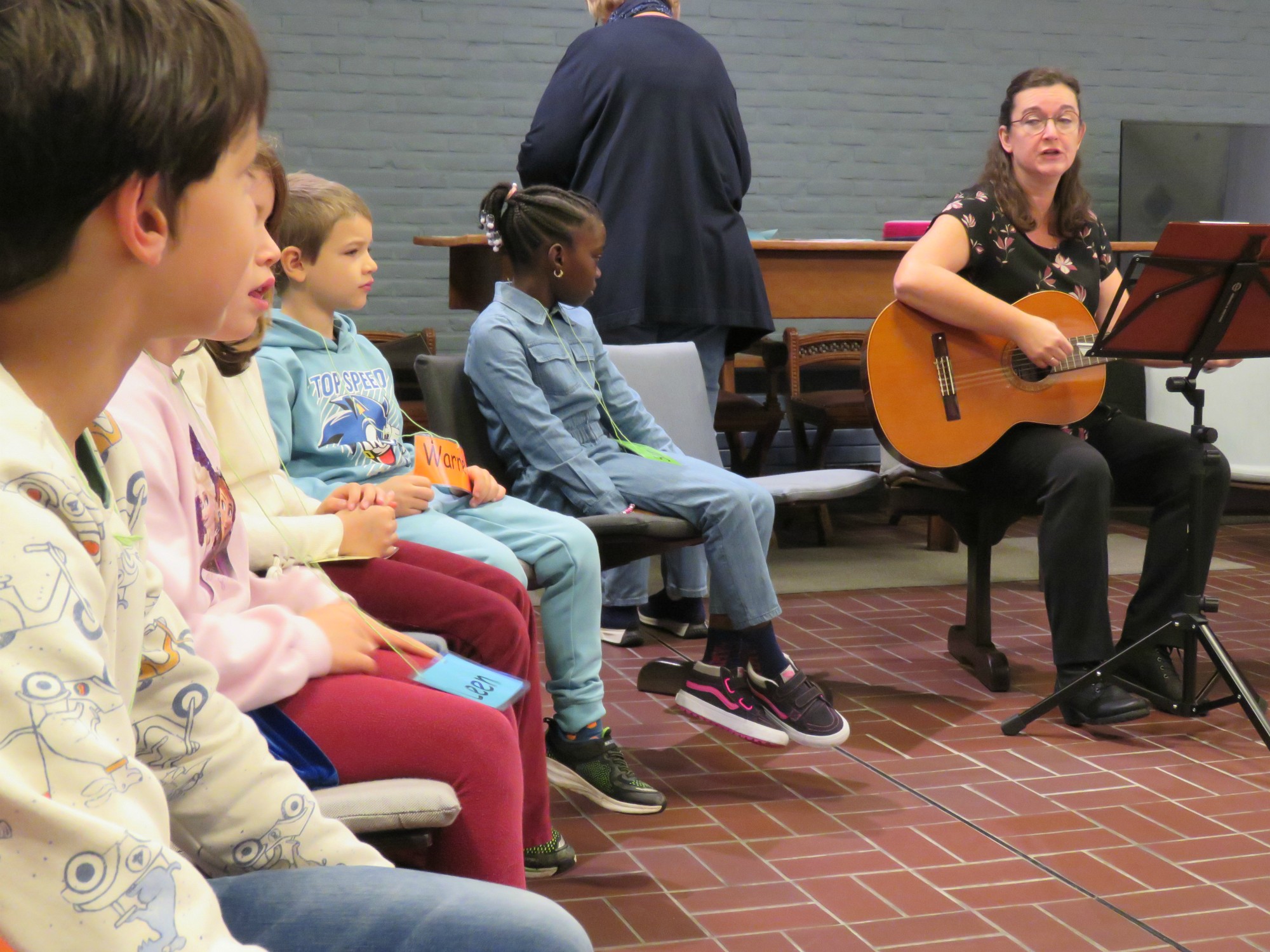 Eerste communicanten 2024 - Juf Marianne met haar gitaar - Ik ben Ik