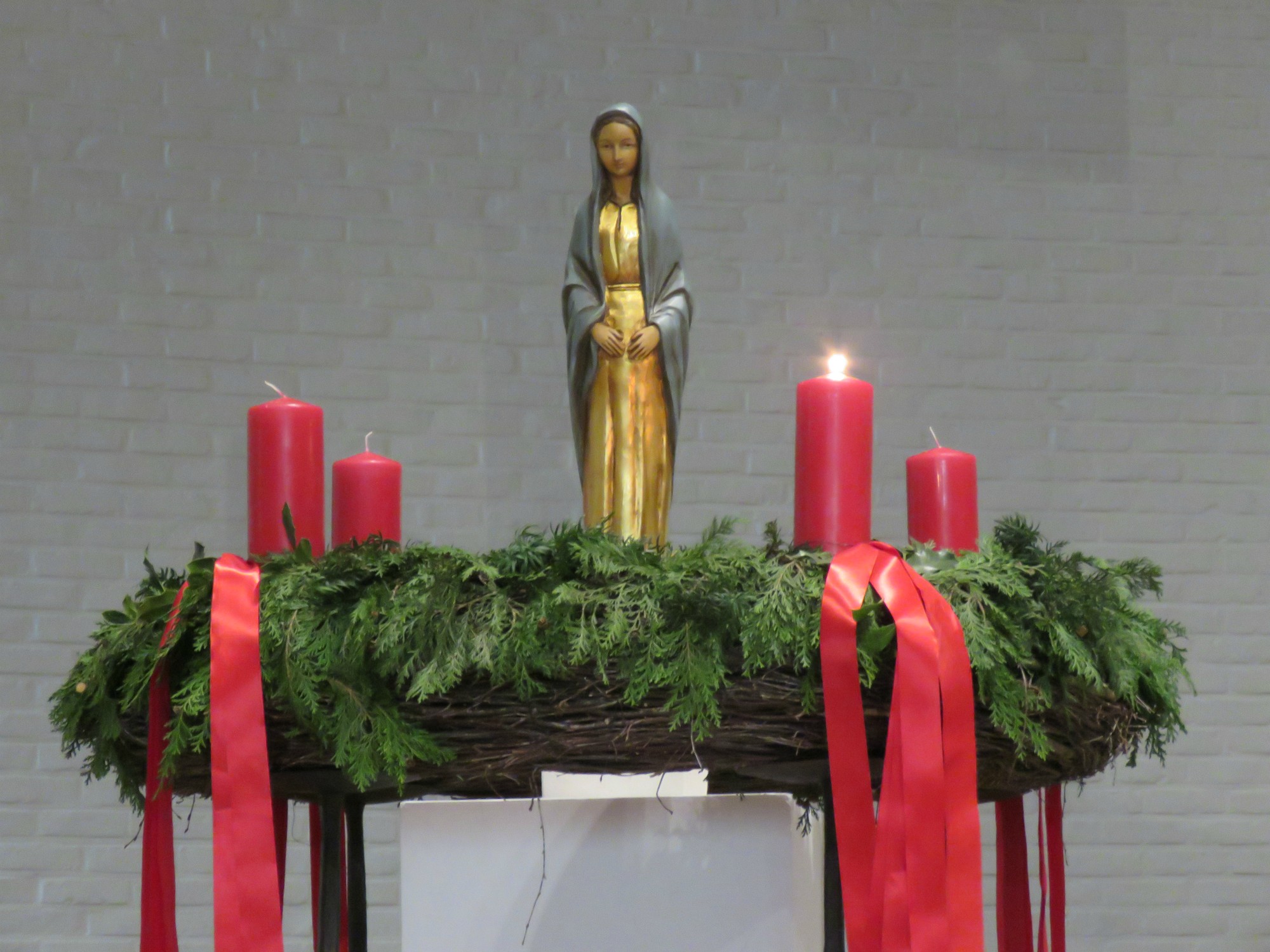 De eerste kaars van de adventskrans wordt aangestoken door een eerste communicant