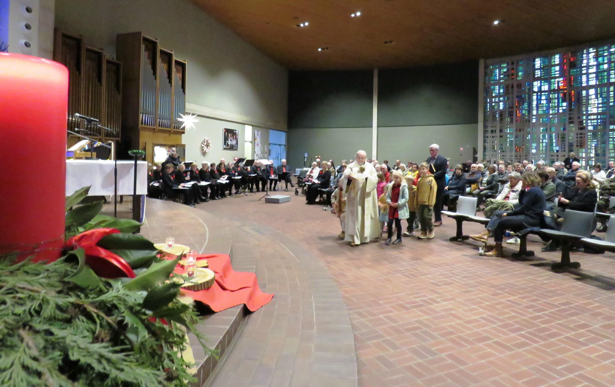 Priester Paul Scheelen legt het Kindje samen met andere kinderen in de kribbe van de kerststal