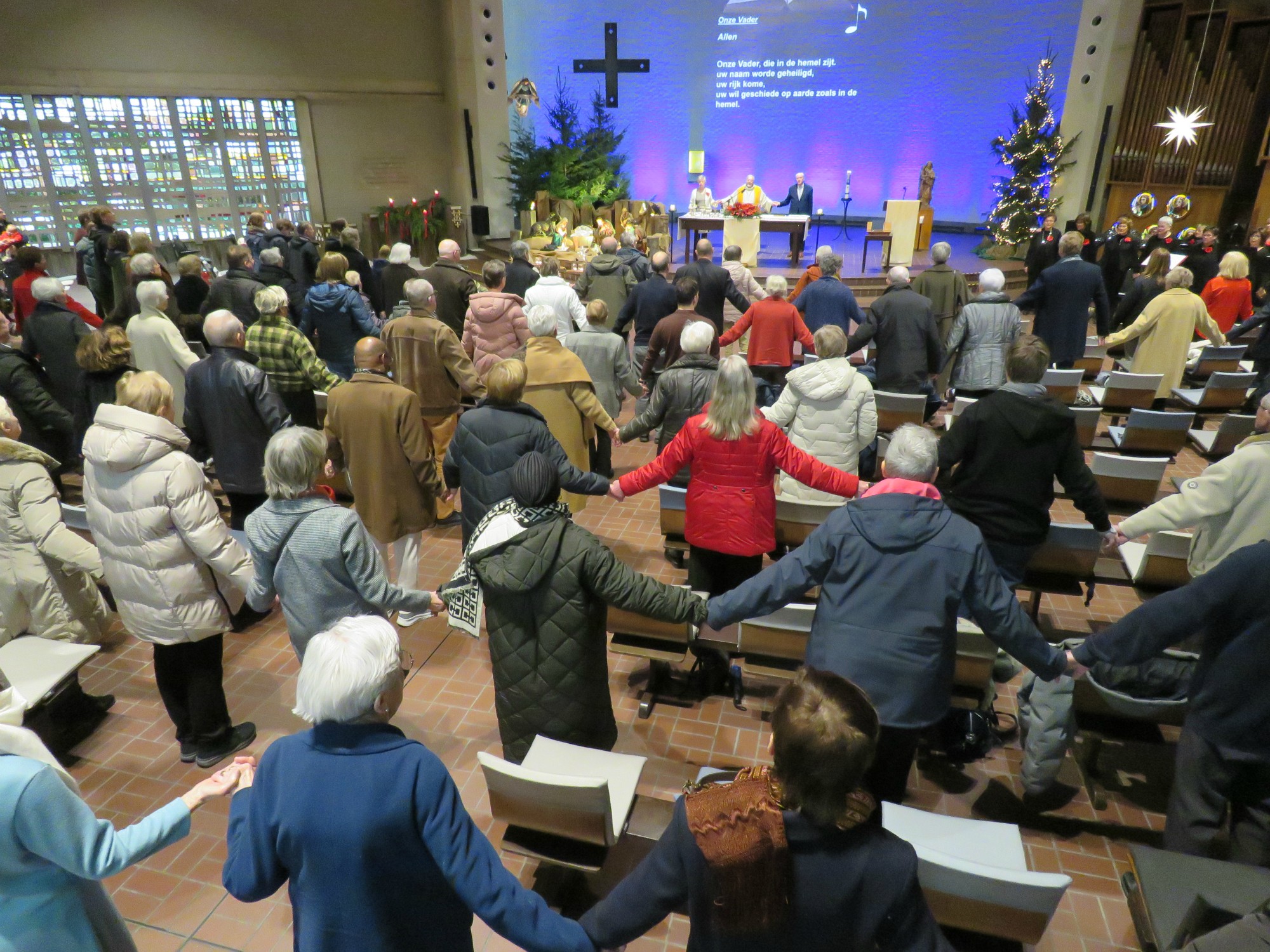 Kerstviering - Het Onze Vader, hand in hand, over de rijen heen